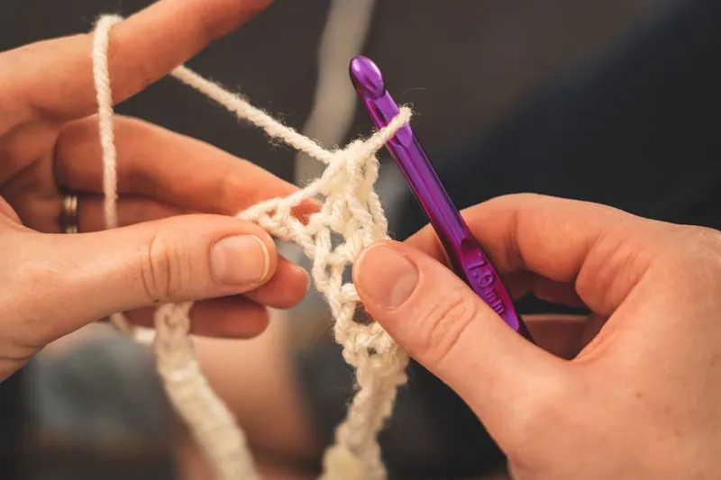 Bunte Wollknäuel und Häkelnadeln als Materialien für eine gehäkelte Handytasche