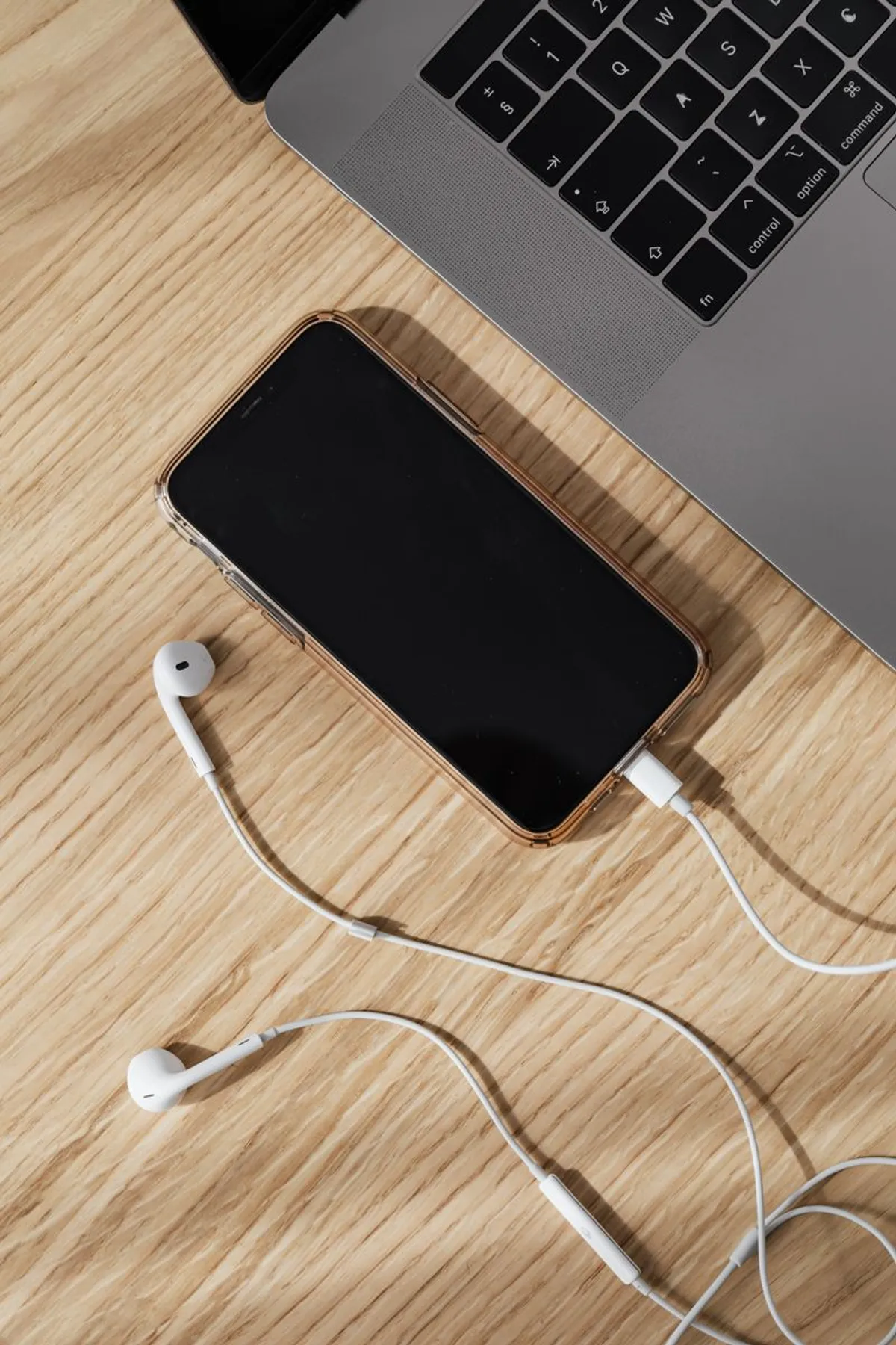Smartphone neben Laptop auf Holztisch - regelmäßige Displayreinigung schützt das Gerät